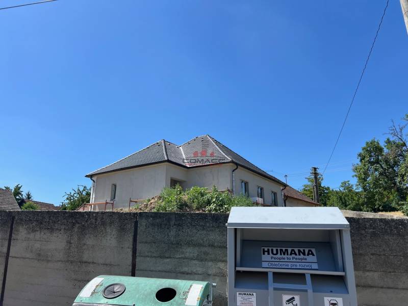 4iz RD Sasinkovo - Rodinný dom v Sasinkove na ulici Sasinkovo za betónovým plotom s modrým nebom.