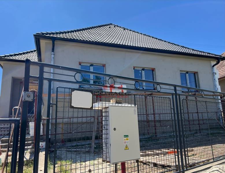 4iz RD Sasinkovo - Rodinný dom v Sasinkove na ulici Sasinkovo s nedokončenou fasádou za kovovým plotom.