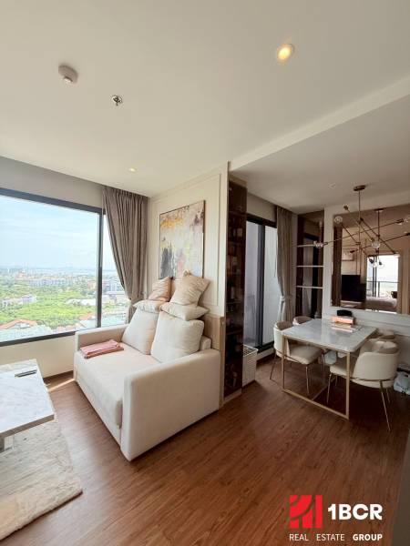 2 SPÁLŇOVÝ APARTMÁN ONCE PATTAYA - Obývacia miestnosť v 3-izbovom byte, svetlé steny, veľké okno, jedálenský stôl.