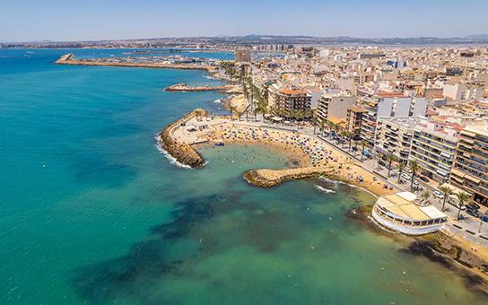 TORREVIEJA - UVÁDZACIE CENY ZA NOVOSTAVBU len 300 metrov od mora - Pobrežie Torrevieja ponúkajúce výhľad na pláž a mestskú panorámu.