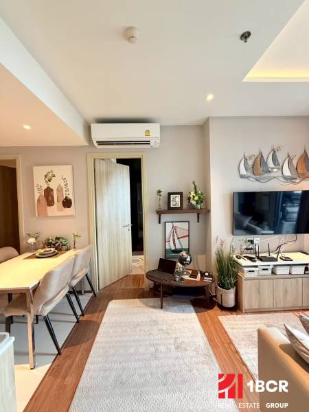 2 SPÁLŇOVÝ APARTMÁN ONCE PATTAYA - Obývacia izba 3-izbového bytu zariadená stolom, stoličkami a dekoráciami na stene.