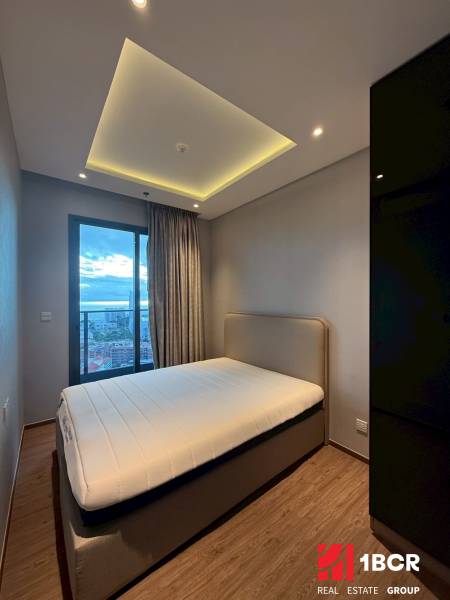 2 SPÁLŇOVÝ APARTMÁN ONCE PATTAYA - Spálňa v 3-izbovom byte s posteľou, vstavanou skriňou a závesmi pri okne.
