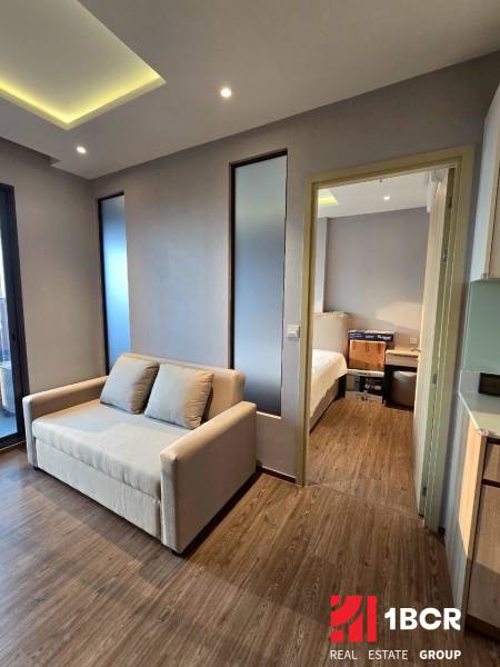 2 SPÁLŇOVÝ APARTMÁN ONCE PATTAYA - Svetlá obývacia izba v 3-izbovom byte s pohovkou a drevenou podlahou.