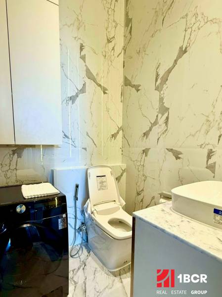 PENTHOUSE ONCE PATTAYA - Kúpeľňa v 4-izbovom byte s toaletou, práčkou a mramorovými stenami.