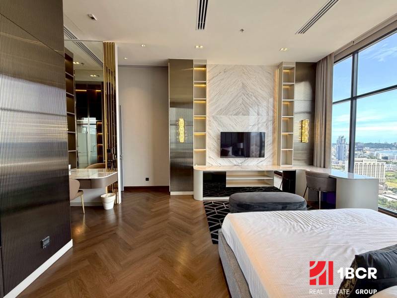 PENTHOUSE ONCE PATTAYA - Luxusná spálňa s výhľadom, drevenou podlahou, televízorom a pracovným stolom v 4-izbovom byte.