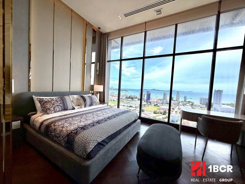 PENTHOUSE ONCE PATTAYA - Spálňa v 4-izbovom byte s veľkým oknom ponúka výhľad na mesto a pobrežie.