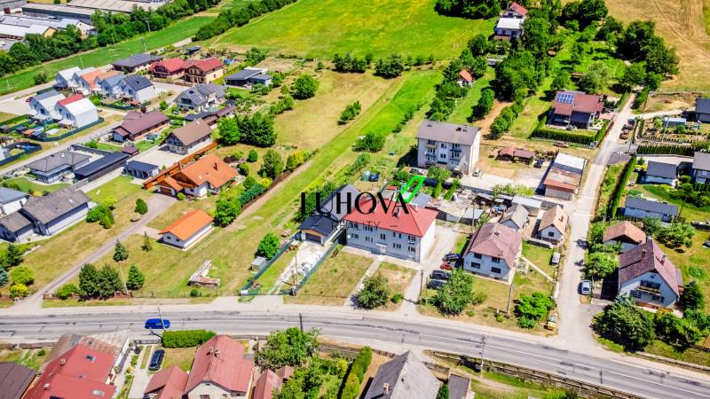 Na predaj 2-izbový byt so záhradkou a garážou! - Letecký pohľad na domy v Púchove s okolitou zeleňou a cestnou infraštruktúrou.