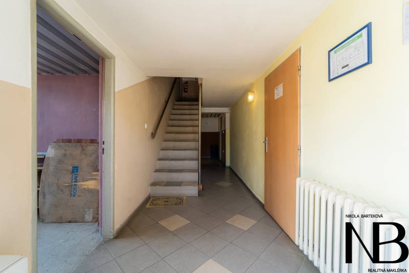 Na predaj polyfunkčný objekt na pozemku 4609 m2, TN - Zámostie - Vstupná chodba so schodmi, dverami a radiátorom v priestoroch Sklady a haly.