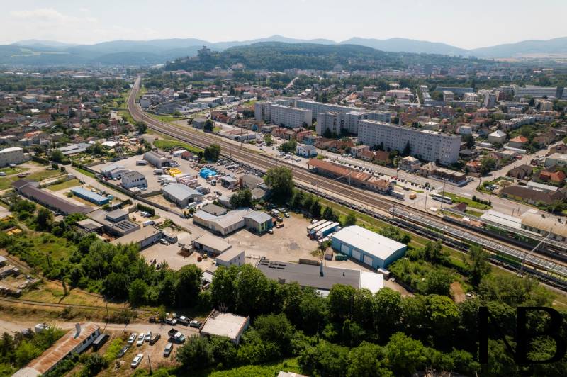 Na predaj polyfunkčný objekt na pozemku 4609 m2, TN - Zámostie - Letecký pohľad na Trenčín, Kasárenskú ulicu a Sklady a haly, v pozadí hory.