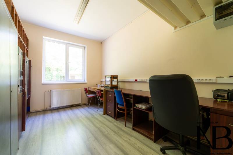 Na predaj polyfunkčný objekt na pozemku 4609 m2, TN - Zámostie - Kancelárska miestnosť so stolmi, stoličkami a skriňou v skladoch a halách.