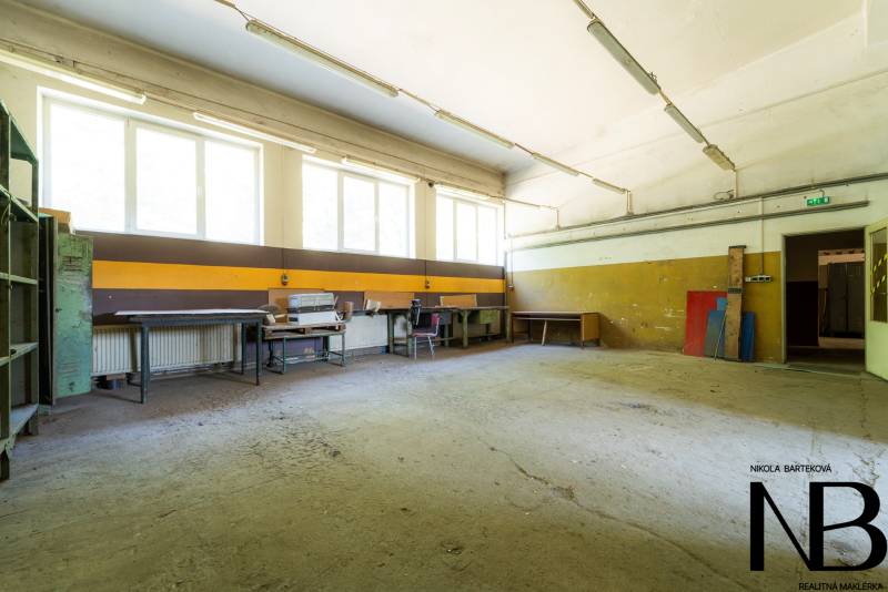 Na predaj polyfunkčný objekt na pozemku 4609 m2, TN - Zámostie - Priestranný interiér, Sklady a haly, s pracovnými stolmi a úložnými regálmi.