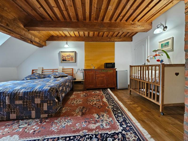 PREDAJ – Apartmánový dom na Donovaloch s 3 samostatnými apartmánmi - Spálňa v rodinnom dome s dreveným stropom, posteľou, detskou postieľkou a kobercom.