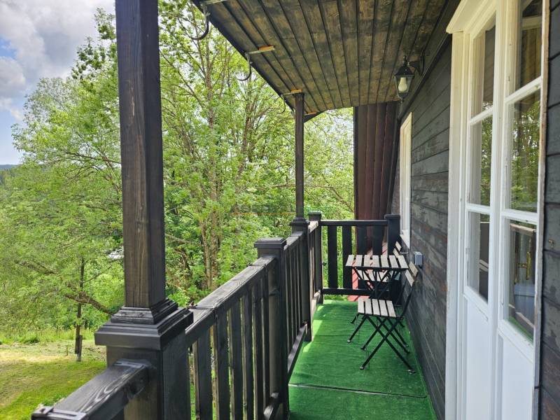 PREDAJ – Apartmánový dom na Donovaloch s 3 samostatnými apartmánmi - Balkón rodinného domu s dreveným zábradlím a výhľadom na prírodu v Donovaloch.