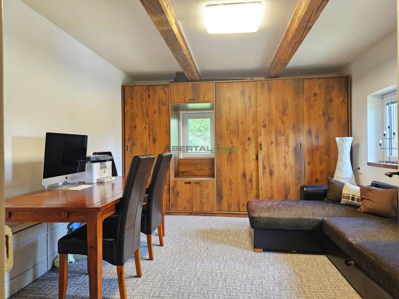 PREDAJ – Apartmánový dom na Donovaloch s 3 samostatnými apartmánmi - Pracovný kút v rodinnom dome so stolom, dvomi stoličkami, drevenou skriňou a pohovkou.