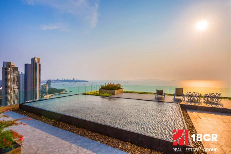 THE RIVIERA WONGAMAT BEACH PATTAYA - Výstavba bytov v Pattayi so strešným bazénom a výhľadom na more pri západe slnka.