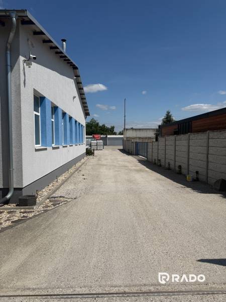 Skladová hala na prenájom 108 m², novostavba | Tureň - Plocha medzi budovami, Sklady a haly v Tureň, betónový povrch, modré okná.