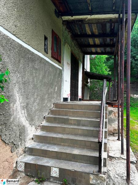 STARŠÍ RODINNÝ DOM, POZEMOK 2476 m2, VEĽKÁ LESNÁ; - Vchod so schodiskom do rodinného domu vo Veľkej Lesnej, obklopený zelenou vegetáciou.