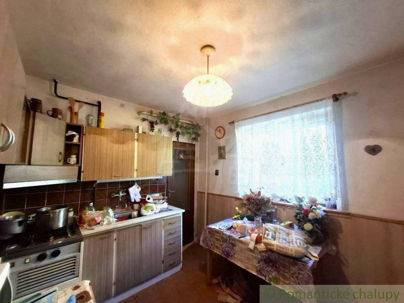 Priestranný poschodový rodinný dom v Lovinobani - Kuchyňa v rodinnom dome s linkou, stolom a kvetmi na okne.
