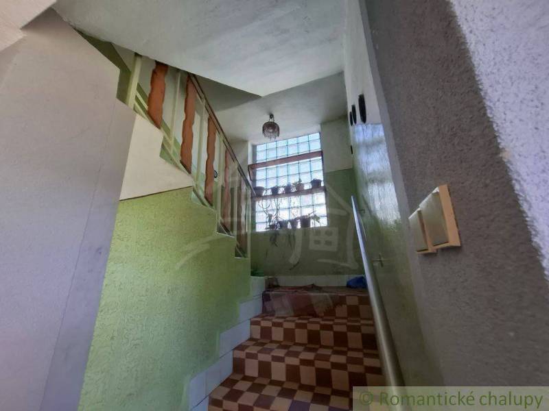 Priestranný poschodový rodinný dom v Lovinobani - Schodisko v rodinnom dome s kvetmi na okne a zábradlím.