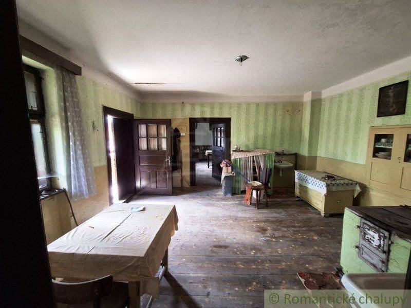 Súbor nehnuteľností určených na revitalizáciu Pohorelá -Nízke Tatry - Interiér rodinného domu s drevenou podlahou, starožitným nábytkom a jednoduchým stolom.