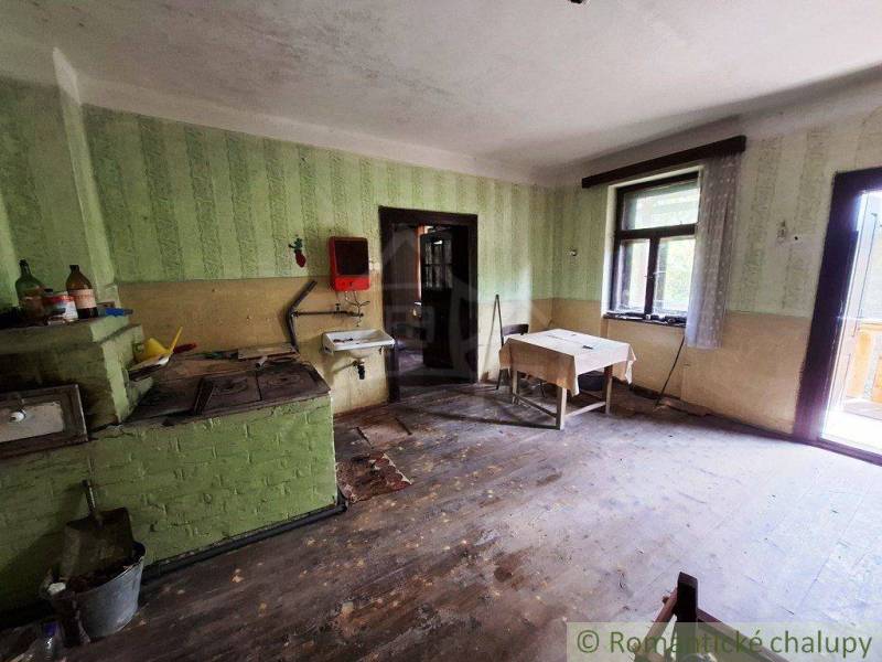 Súbor nehnuteľností určených na revitalizáciu Pohorelá -Nízke Tatry - Kuchyňa v rodinnom dome s jednoduchým zariadením, drevená podlaha a zelené steny.