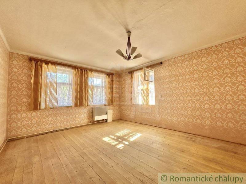 Vidiecky dom v tichej časti obce Gemerská Poloma - Izba v rodinnom dome s drevenou podlahou a tapetami.