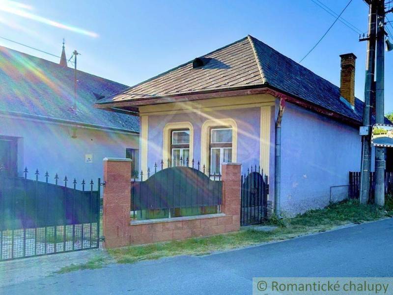 Vidiecky dom v tichej časti obce Gemerská Poloma - Rodinný dom v Gemerskej Polome s farebnou fasádou, silnou ohradou a oknami s mrežami.