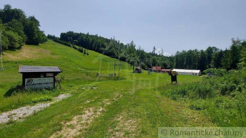 Lyžiarske stredisko Skiland Stará Myjava, okr. Myjava na predaj - Zelená lúka a lesy s obchodnými priestormi na Starej Myjave pod slnečnou oblohou.
