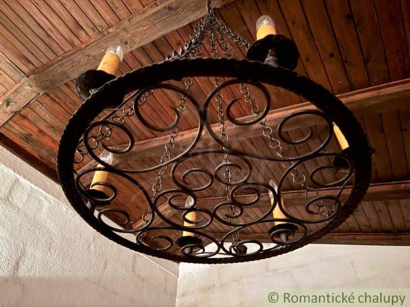 Murovaná chata pod Pajštúnom, váš nový domov v lese, Stupava - Kovaná lampa so sviečkami v interiéri rodinného domu s dreveným stropom.
