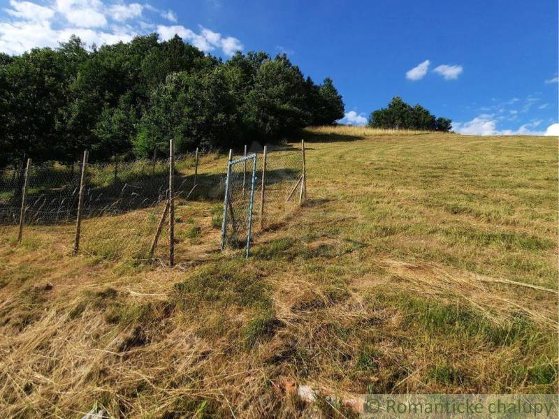 Na predaj slnečný pozemok 5854 m² – Župkov, tichá lokalita s výhľadom - Plot na trávnatom kopci v záhradách Žarnovice, v pozadí lesná krajina.