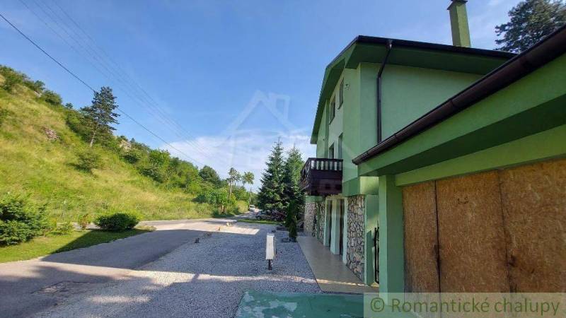 5-izbový štýlový dom pod lesom v obci Dobrá Voda na predaj - Rodinný dom v Dobrej Vode s cestou, okolitou prírodou a zelenou fasádou.