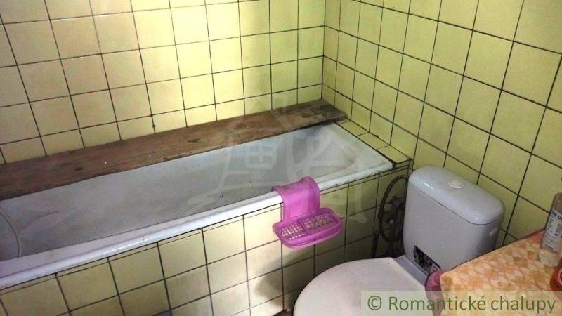Útulný vidiecky domček, Fričovce - Kúpeľňa v rodinnom dome s vaňou a toaletou, obklopená žltými kachličkami.
