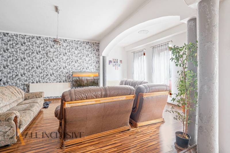 NA PREDAJ PRIESTRANNÝ RODINNÝ DOM, DUNAJSKÁ STREDA - Obývacia izba s koženou sedačkou, vzorovanou tapetou a kvetinou v Rodinnom dome.