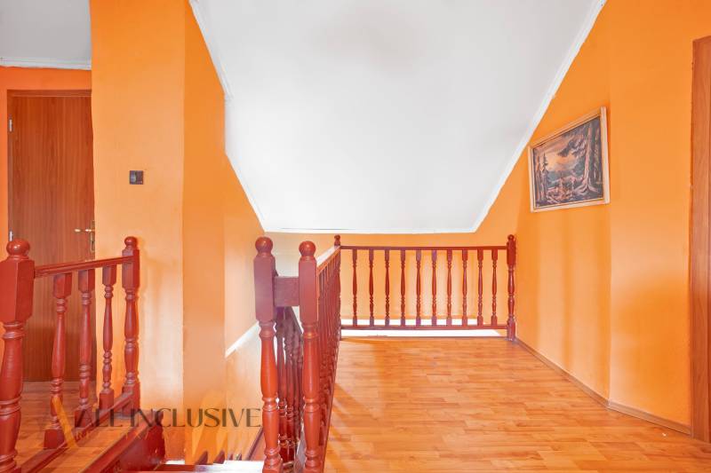 NA PREDAJ PRIESTRANNÝ RODINNÝ DOM, DUNAJSKÁ STREDA - Interiér rodinného domu s oranžovými stenami, drevenou podlahou a zábradlím schodiska.