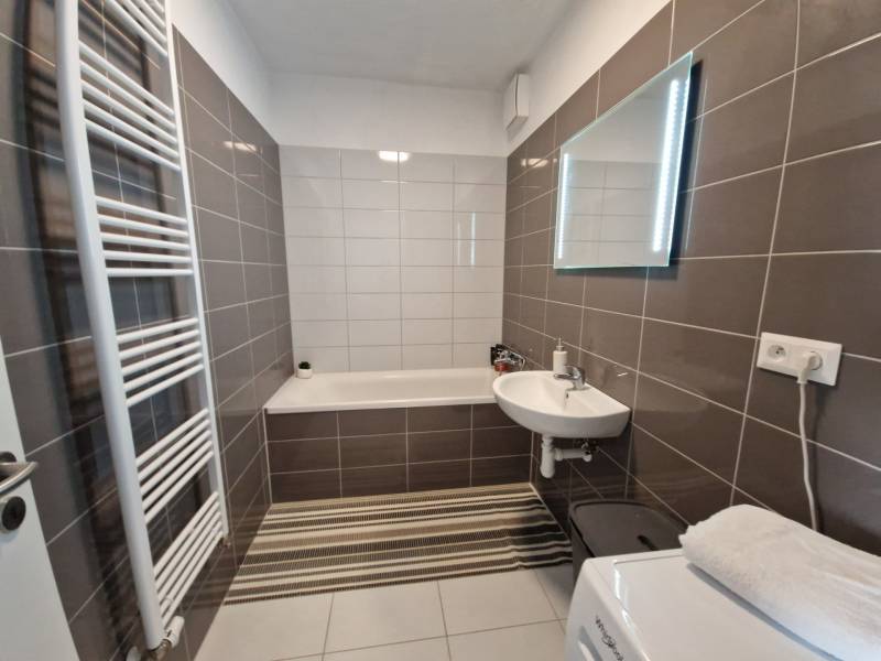 2 IZBOVÝ BYT S KRYTÝM PARK. MIESTOM, NOVOSTAVBA **Pri parku** Senica  - Kúpeľňa v 2-izbovom byte s vaňou, umývadlom, zrkadlom a rebríkovým radiátorom.