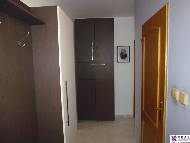 3-izb. byt s loggiou: KOMPLET ZARIADENÝ a ZREKONŠTR., 65 m2 - Lomnická - Chodba v 3-izbovom byte s tmavým nábytkom, bielymi stenami a drevenými dverami.