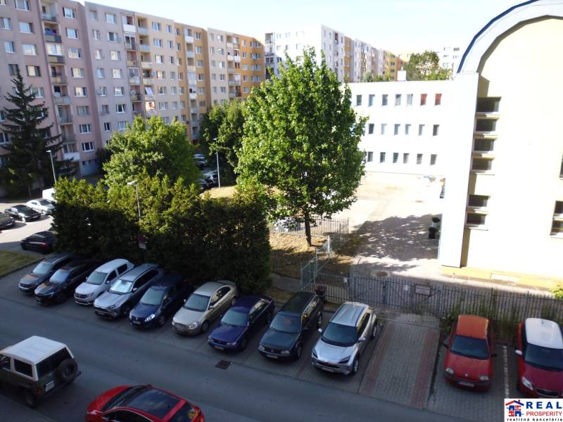 3-izb. byt s loggiou: KOMPLET ZARIADENÝ a ZREKONŠTR., 65 m2 - Lomnická - Parkovisko a bytové domy na ulici Lomnická v Prešove, obklopené zeleňou.