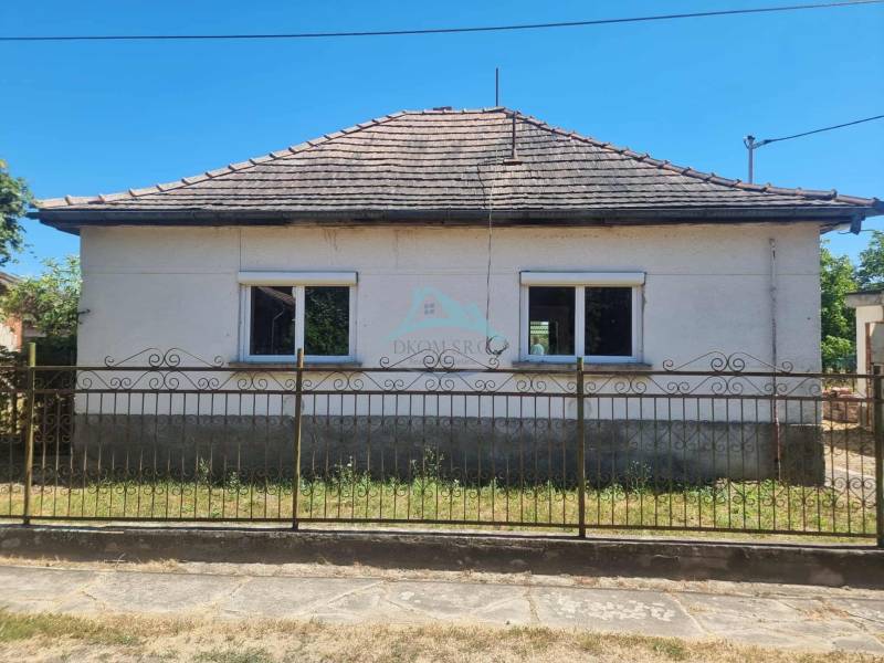 Rodinný dom na predaj, obec Ipolvece, Maďarsko - Rodinný dom v Ipolyveci s dvomi oknami a šikmou strechou za kovovým plotom.