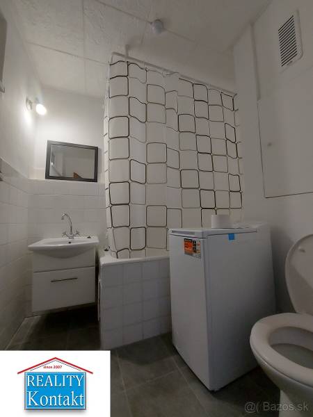 Na predaj 1-izbový byt - Nové Zámky - Kúpeľňa s práčkou, sprchovým závesom a toaletou v 1-izbovom byte.