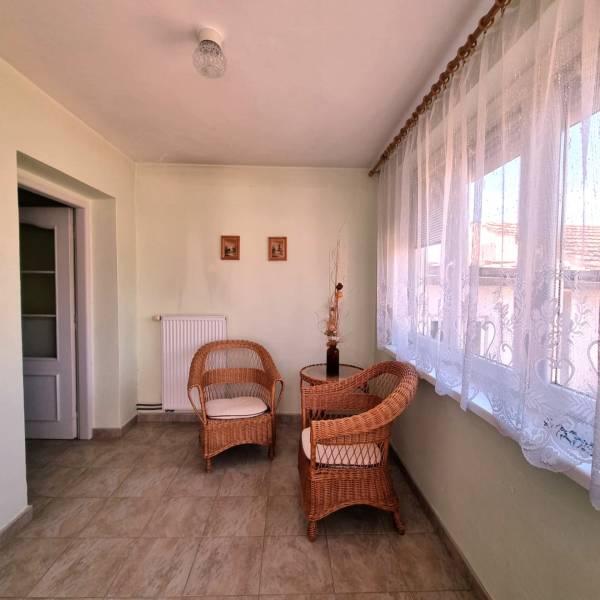 Rodinný dom na predaj - Malacky. - Priestranná miestnosť rodinného domu s prúteným nábytkom a elegantnými záclonami.