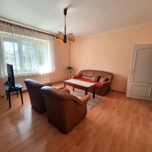 Rodinný dom na predaj - Malacky. - Obývačka rodinného domu so sedačkou, kreslami, televízorom a dreveným stolom na koberci.