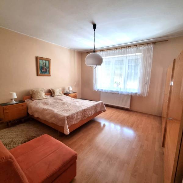 Rodinný dom na predaj - Malacky. - Spálňa v rodinnom dome s dvojposteľou, obrazom a veľkým oknom.