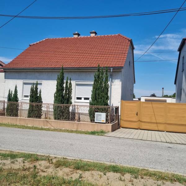 Rodinný dom na predaj - Malacky. - Rodinný dom na Riadku v Malackách s červenou strechou, predzáhradkou a drevenou bránou.