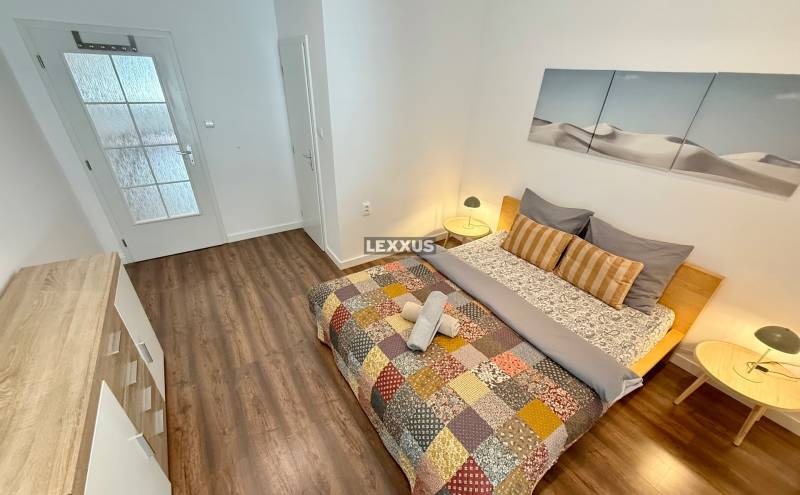 2i zariadený byt , Laurinská ul., BA I.- Staré Mesto, 57,30m2 - Spálňa v 2-izbovom byte s farebným prehozom na posteli a drevenou podlahou.