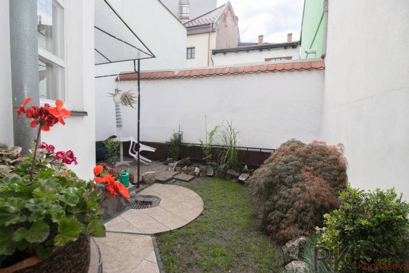 Centrum Košíc- Vrátna ulica, 2.izb. byt s terasou - Malá záhradka pri 2-izbovom byte s dlažbou, rastlinami a dekoráciou z kameňov.