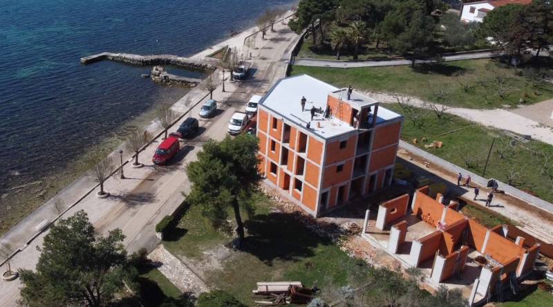 CHORVÁTSKO - Nové apartmány 3 m od mora (5i) - ostrov VIR, Zadar - Stavebná budova pri mori vo meste Vir s prístupovou cestou a zeleňou.
