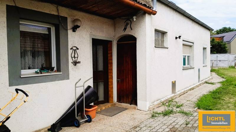 Predaj rodinného domu, Neusiedl am See - Rodinný dom v 2473 Potzneusiedl s bielou fasádou a vstupnými drevenými dverami.