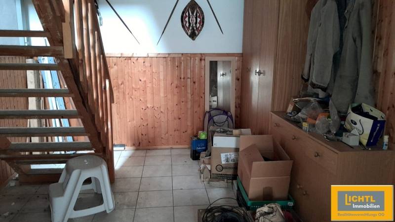 Predaj rodinného domu, Neusiedl am See - Drevené schodisko a úložný priestor v rodinnom dome s krabicami a kabátmi.