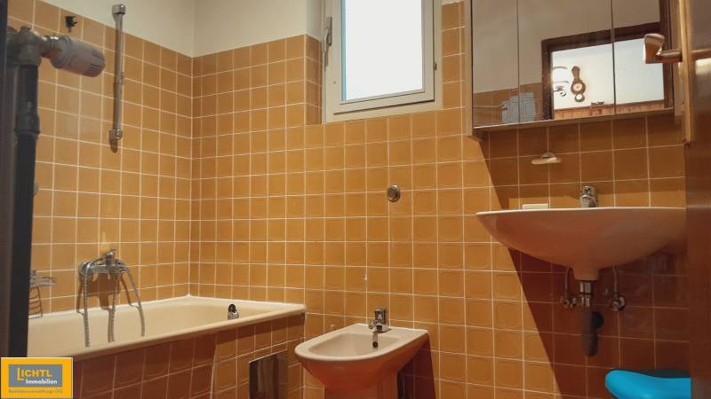 Predaj rodinného domu, Neusiedl am See - Kúpeľňa s oranžovými kachličkami v rodinnom dome, obsahuje vaňu, bidet a umývadlo.