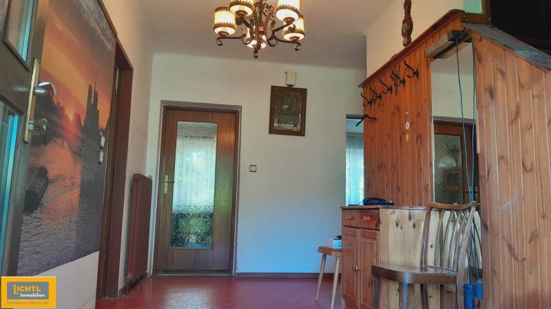 Predaj rodinného domu, Neusiedl am See - Chodba v rodinnom dome s dreveným obložením, zrkadlom a dekoratívnym lustrom.